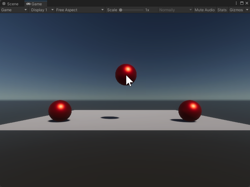 An image of the Game view. A plane has two red spheres sitting on top of it. A third red sphere, shown with the user's cursor on top of it, floats between the other two spheres above the plane.